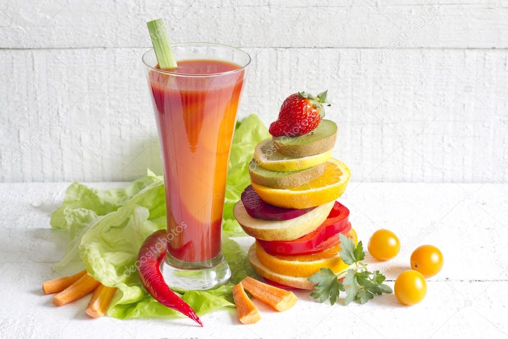 Fresh spring juice and pile of slice fruits and vegetables