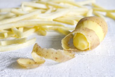 Patates soyma ve beyaz tahta üzerinde patates kızartması ile