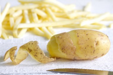 Patates soyma ve beyaz tahta üzerinde patates kızartması ile