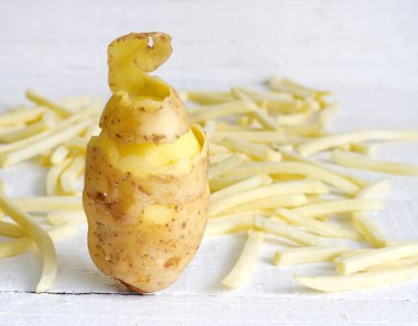 Patates soyma ve beyaz tahta üzerinde patates kızartması ile
