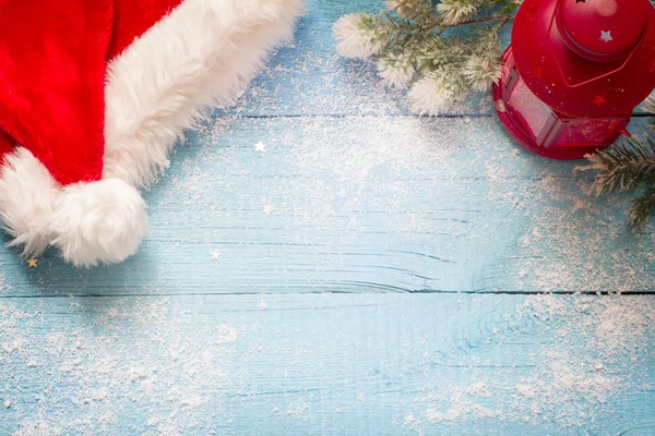 Santa claus şapka ve mavi karlı panoları soyut üzerinde fener — Stok fotoğraf