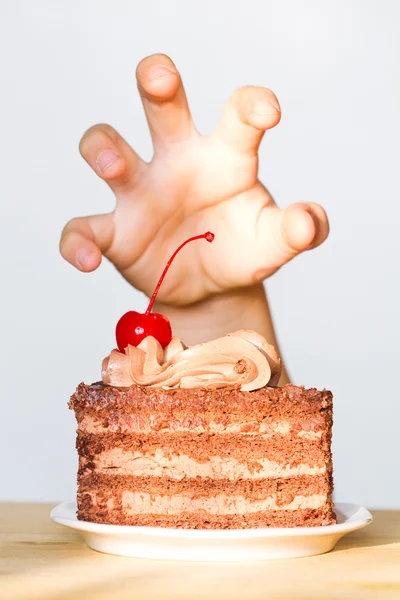 Zachłanność na słodycze koncepcja z ręki i czekoladowe ciasto — Zdjęcie stockowe