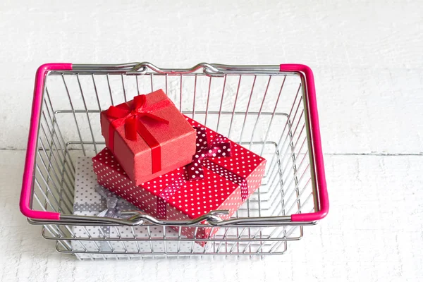 Gifts in shopping basket on a white christmas symbol — Stock Photo, Image