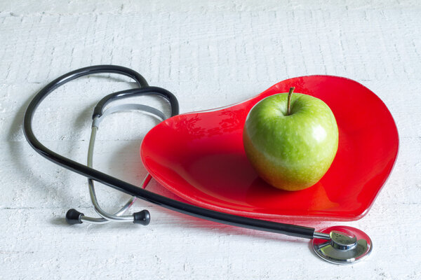Stethoscope and a red heart plate diet concept on white boards