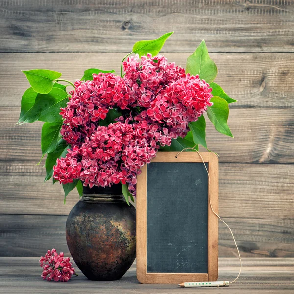 Red flowers in vase on wooden background — Stok fotoğraf