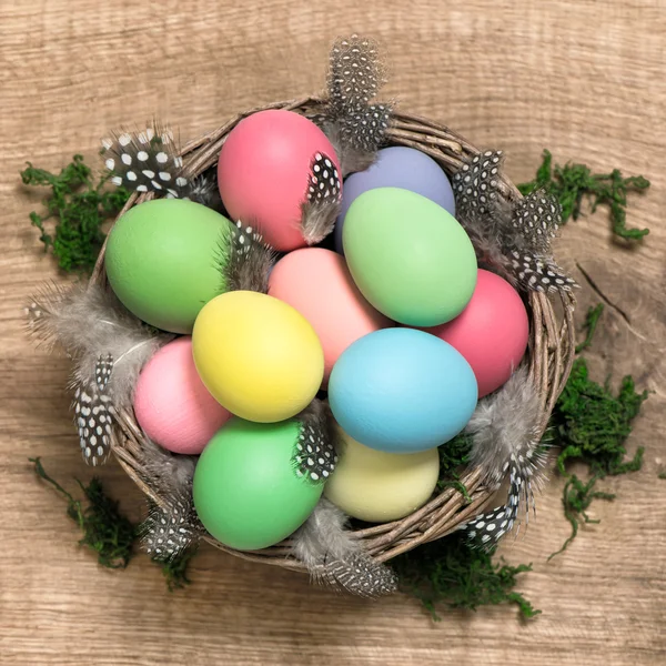 Huevos de Pascua en cesta sobre fondo de madera —  Fotos de Stock