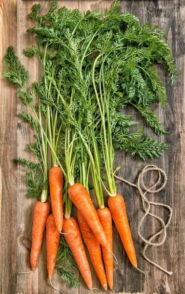 Carota fresca radici foglie verdi rustico fondo in legno — Foto Stock