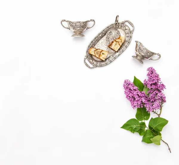 Fliederfarbener Blumenstrauß mit Kuchen und Silbergeschirr — Stockfoto