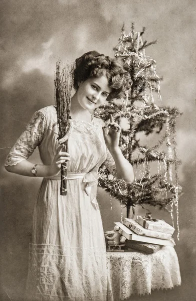 Young woman with christmas tree and gifts. Antique picture Stock Picture