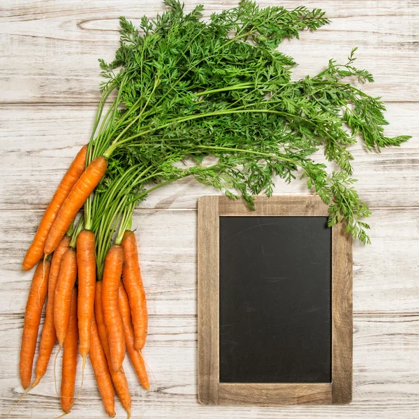 Verse wortelen wortels groene bladeren en schoolbord natuurvoeding — Stockfoto