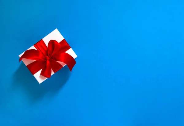 Witte Geschenkdoos Met Rood Lint Strik Blauwe Achtergrond — Stockfoto