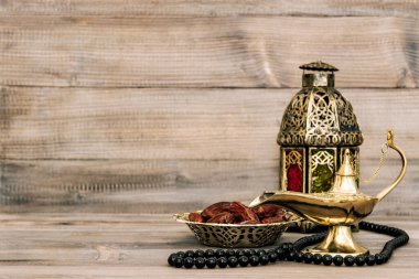 Doğu lambası ve ahşap arka planda hurmalar. Arapça tespihli yaşam
