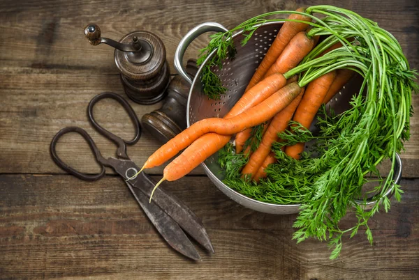 Zanahorias frescas con utensilios de cocina vintage en bac de madera rústica — Foto de Stock