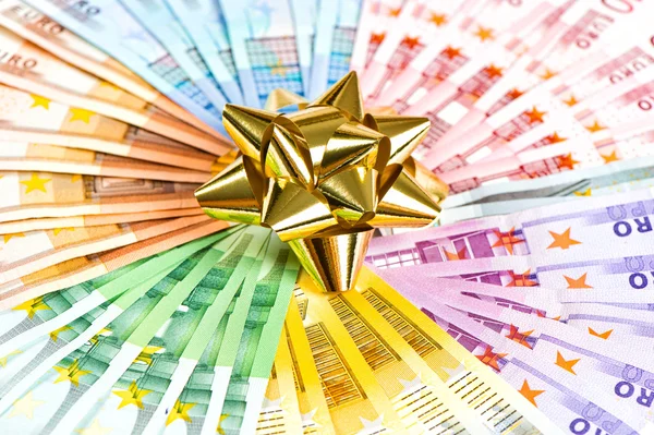 Soldi come regalo. nastro dorato sullo sfondo delle banconote in euro — Foto Stock