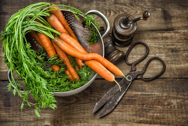 Zanahorias frescas con utensilios de cocina vintage en bac de madera rústica — Foto de Stock