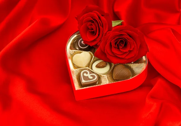 Red roses and chocolate pralines in heart shape gift box — Stock Photo, Image