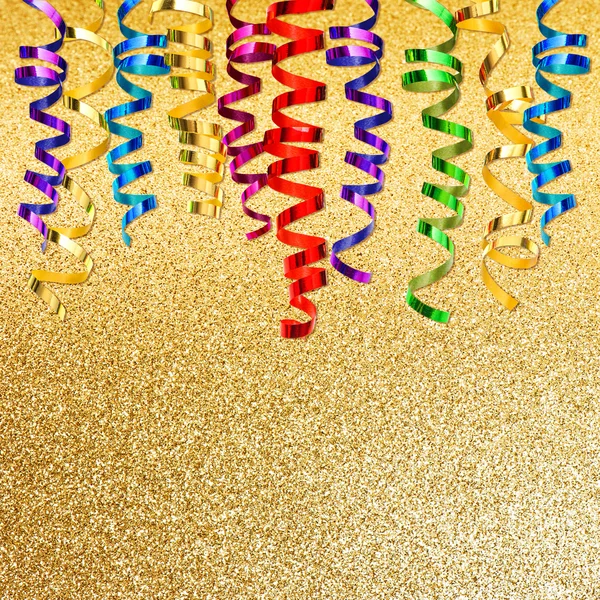 Bunte Luftschlange über goldenem Hintergrund. Partydekoration — Stockfoto