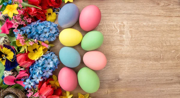 Lente bloemen en gekleurde eieren. — Stockfoto
