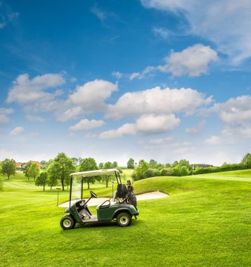 Bir golf sahası golf arabasında. Yeşil alan ve bulutlu mavi gökyüzü