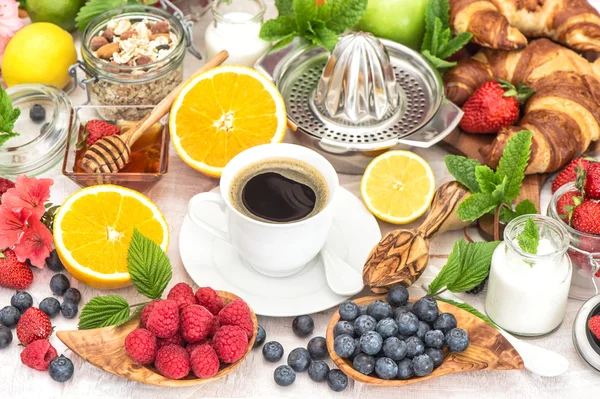 Ontbijttafel instellen met koffie, croissants, muesli, honing. — Stockfoto