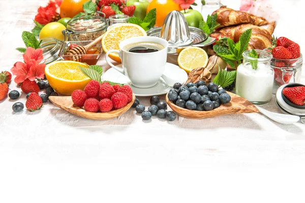 Gesunder Frühstückstisch mit Kaffee, Croissants, Müsli, frischen Beeren, Früchten — Stockfoto