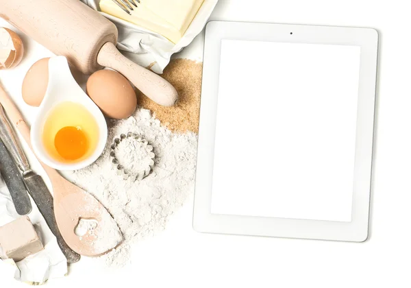 Notebook tablet pc and baking ingredients eggs, flour, yeast — Stock Photo, Image