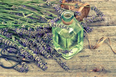 Ahşap arka plan üzerinde taze çiçekler ile bitkisel lavanta yağı