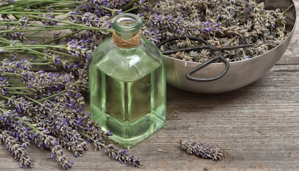 Aceite de lavanda con flores frescas y tijeras sobre fondo de madera —  Fotos de Stock