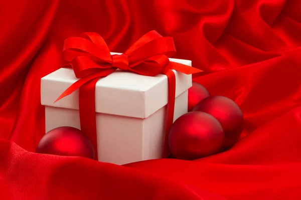 White gift box with christmas balls decoration over red silk — Stok fotoğraf