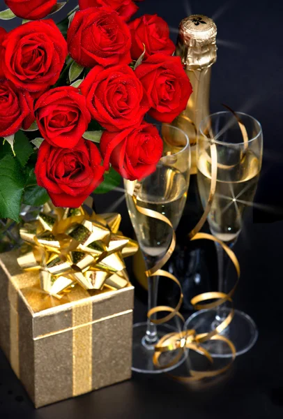 Rosas vermelhas, champanhe e presente dourado. Decoração festiva — Fotografia de Stock