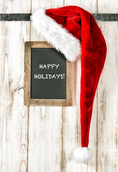Rote Weihnachtsmütze und Kreidetafel. Weihnachtsdekoration glückliche Feiertage — Stockfoto
