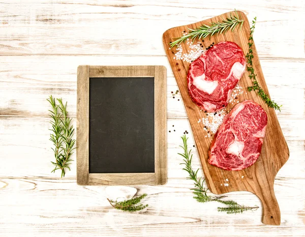 Raw fresh meat with herbs, spices and blackboard. Food backgroun — Stock fotografie