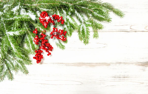 Immergrüner Ast mit roten Beeren auf hölzernem Hintergrund — Stockfoto