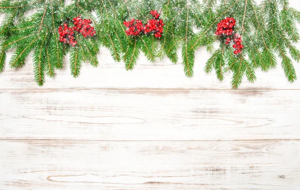 Christmas tree branch with red berries and falling snow — Stockfoto