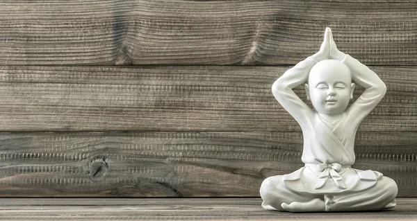 Сидячий Будда. Біла статуя ченця на дерев'яному фоні — стокове фото
