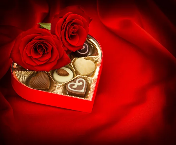 Rosa vermelha e pralines de chocolate caixa de presente do coração — Fotografia de Stock