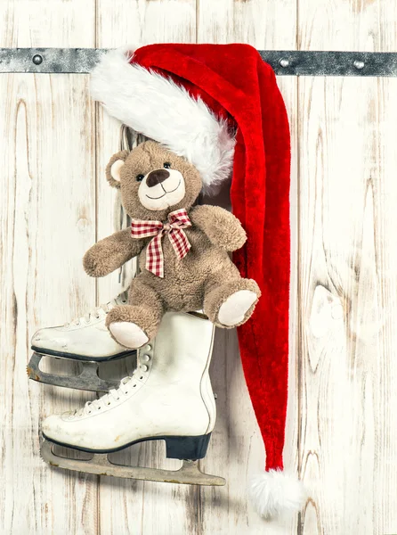 Weihnachtsdekoration. Rote Weihnachtsmütze, Teddybär, Schlittschuhe Stockbild