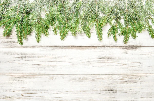 Vuren takjes met sneeuw op lichte houten textuur. Kerstmis — Stockfoto