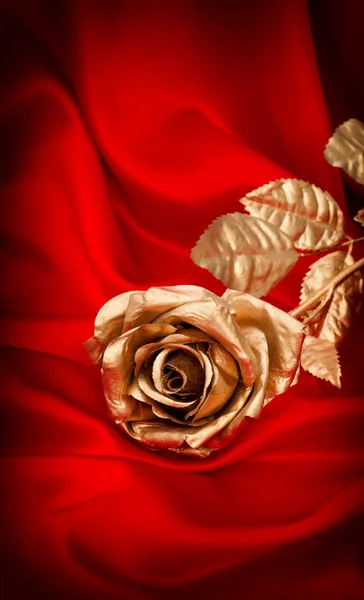 Zlatá růže květ na červené saténové — Stock fotografie