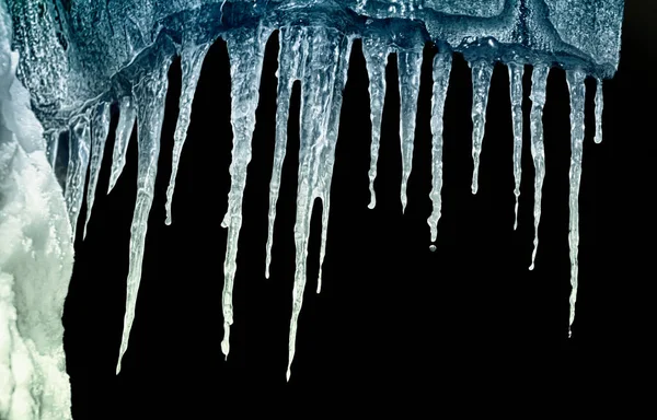 Kara arkaplan üzerindeki bir mahzendeki buz saçakları dizisi kırpmayı izole et