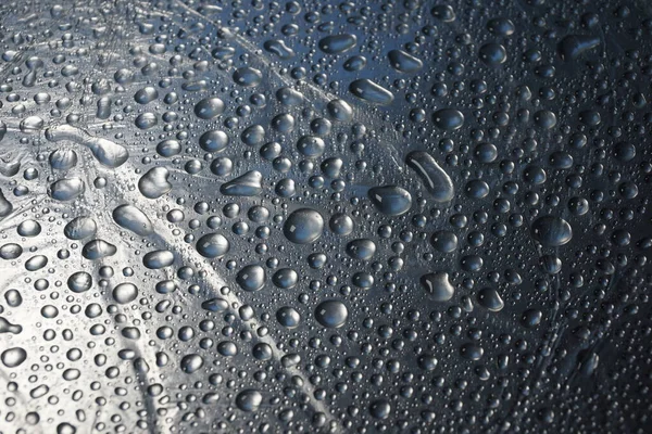 Metal yüzey dokusuna su damlaları. Arka plan parlak metal yüzey.