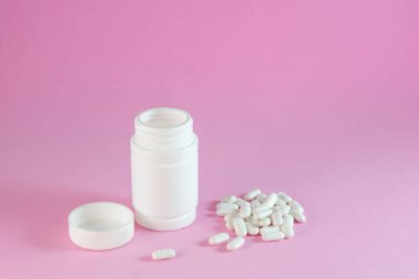 Beriberi kavanozundan ve kapsüllerden çıkan vitamin kompleksi granüller tabletleri yakın plan pembe arka plan