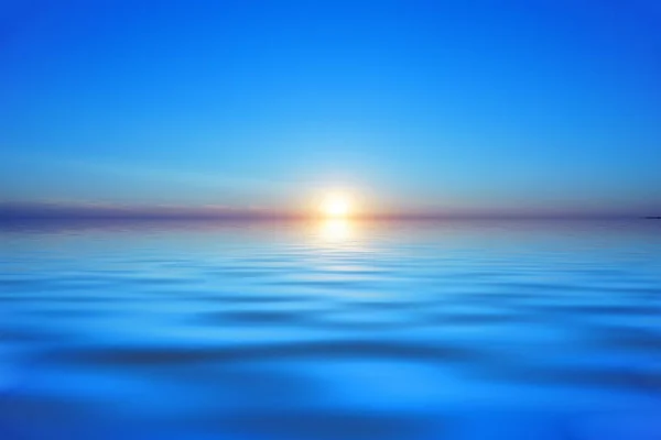 Deniz ya da göl üzerinde gün batımı. Mor turuncu güneş mavi suya huzur verdi. Günbatımını izle. güzel su manzarası