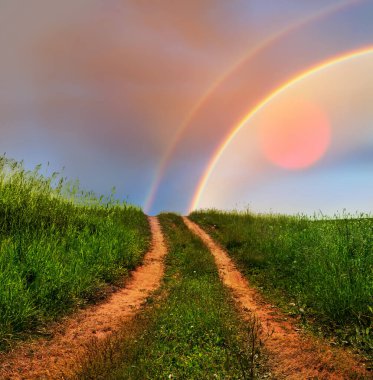 Gökkuşağının içinden cennete giden yol kavramı. Kırsal yol gökyüzüne çıkar batan güneş ve gökkuşağı