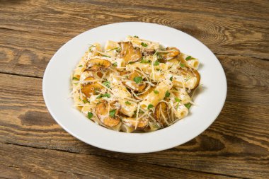 Mantarlı makarna, beyaz şarap ve kırsal bir masada beyaz tabakta pırasa. Kapat.. 