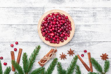 Tahta kasede çiğ yaban mersini, baharat ve hafif ahşap arka planda köknar dalları. Üst Görünüm - Resim