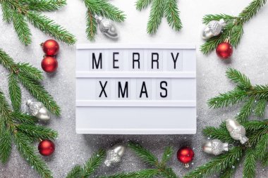 Üzerinde MERRY XMAS, gümüş ve kırmızı noel topları ve köknar ağacı dalları olan ışık kutusu. Kar efektli Noel kompozisyonu - Görüntü