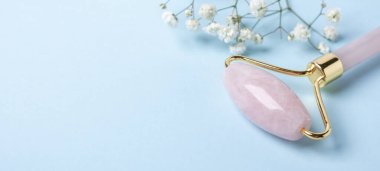 Mavi arka planda yüz silindiri ve çingene çiçeği. Yüz bakımı için masaj aracı, SPA güzellik tedavi konsepti - Görüntü