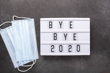 Elveda mesajı içeren ışık kutusu. 2020, karanlık arka planda tıbbi maske. Üst Manzara. Yeni yıl kutlaması. Mutlu yıllar 2021 kavramları - Görüntü