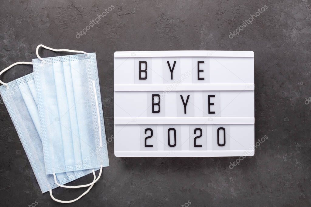 Lightbox with text BYE BYE 2020 with medical mask on dark background. Top view. New year celebration. Happy New Year 2021 concepts - Image